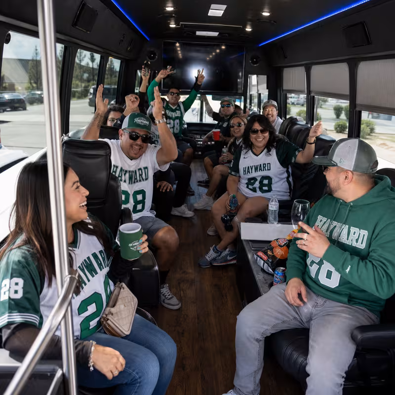 Group boarding a white charter bus for Sporting Event Transportation transportation in Hayward